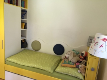 Čalúnené prvky vložené na obklad za posteľou.