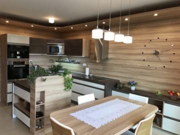 Moderná kuchyňa s použitím laminovaného materiálu v dekore v kombinácii s jedálenským stolom