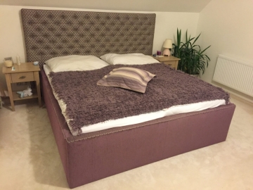 Manželská posteľ s dizajnovým látkovým poťahom.